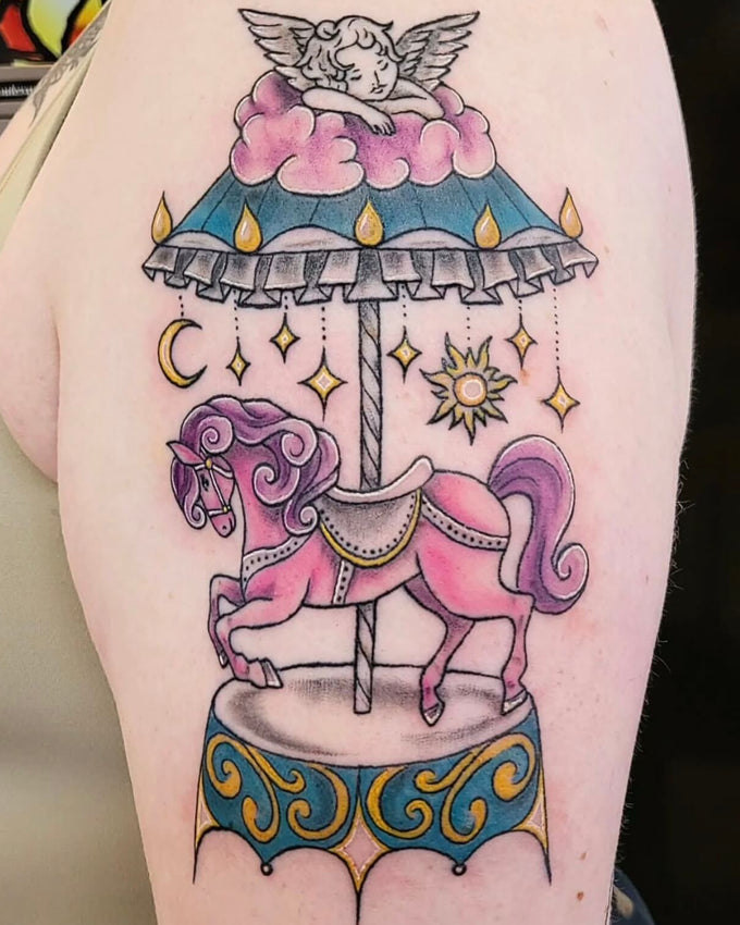 Colorful tattoo of a carousel horse and cloud design on a person's arm.