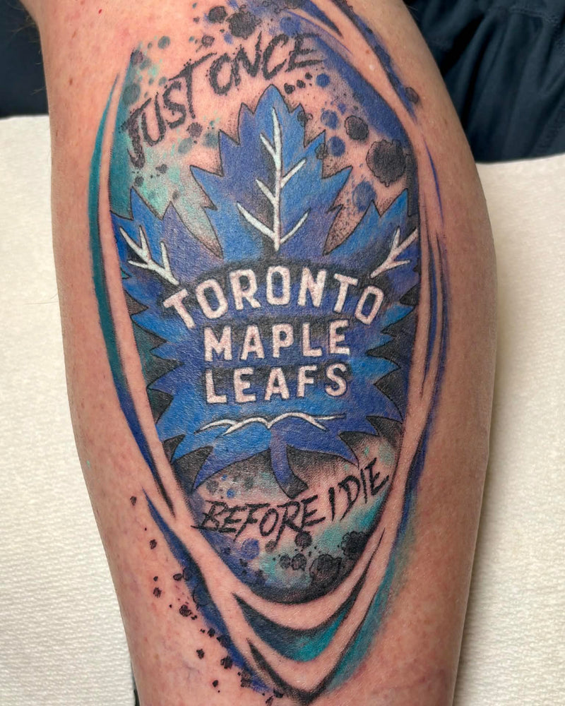 Tattoo of Toronto Maple Leafs design on a person's arm with blue and black colors.