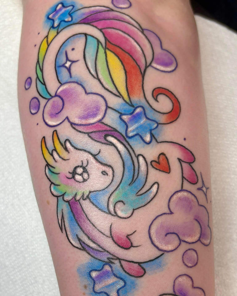Colorful tattoo of a unicorn and rainbow dragon on a person's arm.