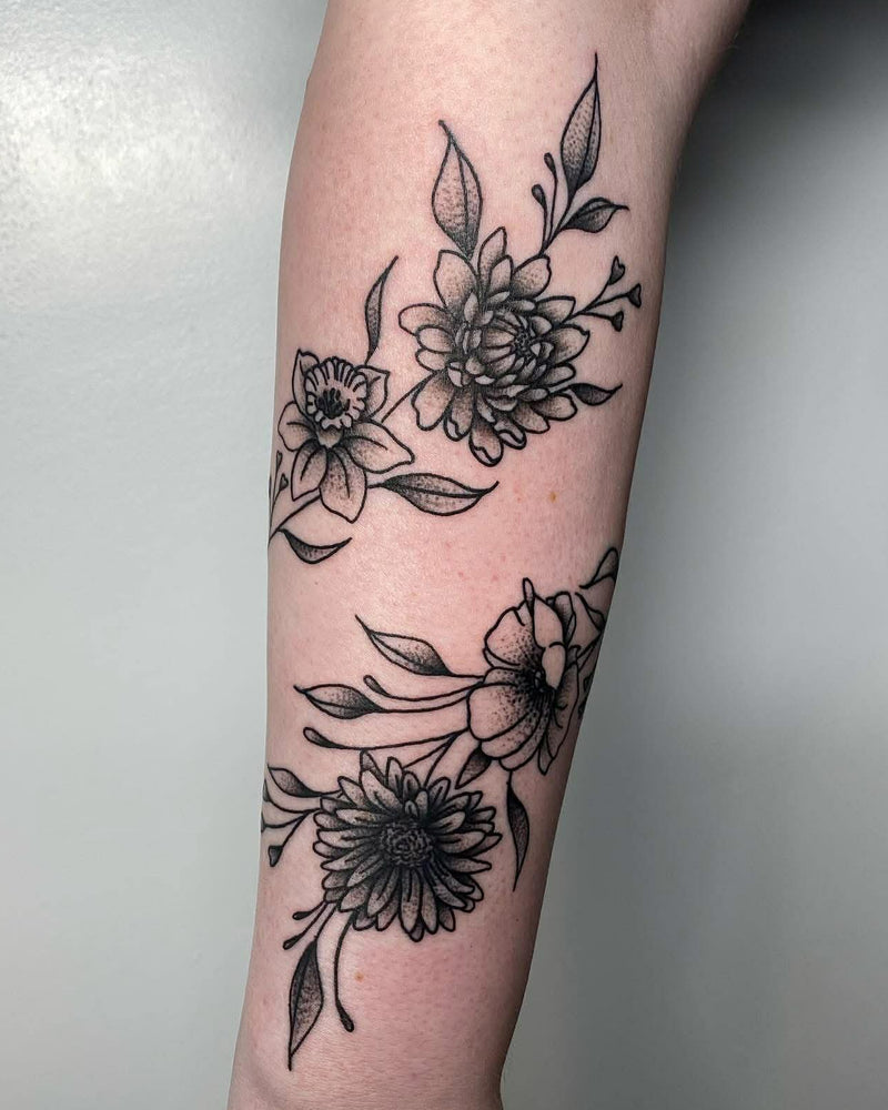 Black floral tattoos on a person's arm with a neutral background