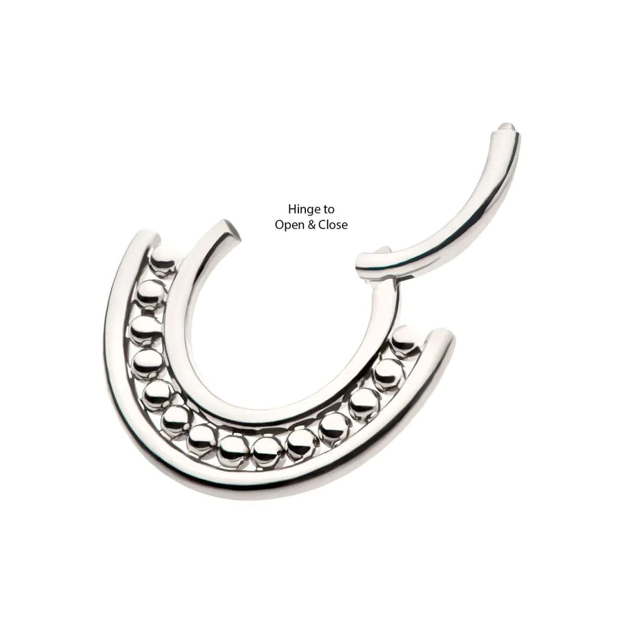 A polished silver or titanium hinged septum clicker jewelry piece, featuring a central row of small, reflective metallic beads nestled between two smooth outer bands, shown in an open position to highlight the hinge.